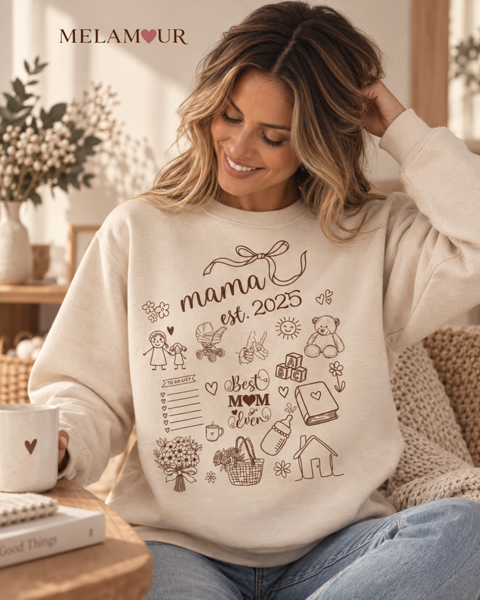 Camisola bege Mama Est. 2025 · Memórias Ilustradas com laço, ilustrações de bebé e a frase Best Mom Ever
